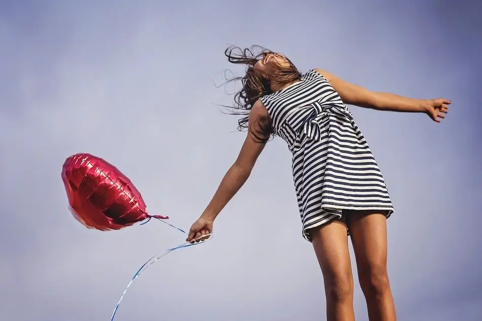 niña saltando con un globo
