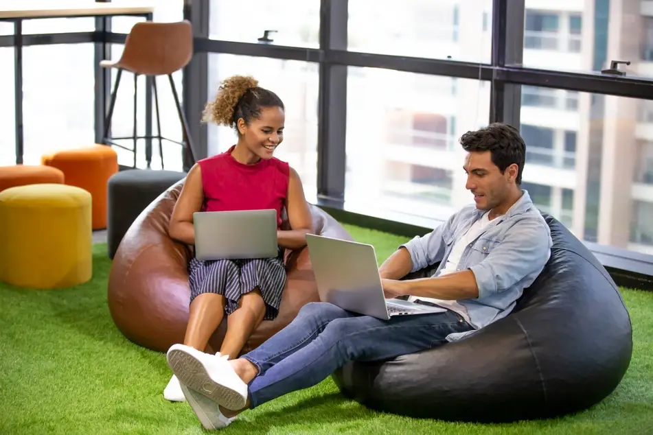 Man and woman sit in bean bag chairs at office