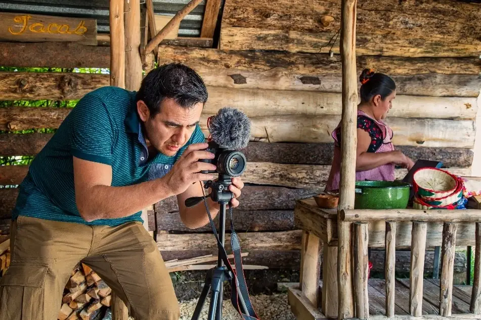 Fotógrafo hispano tomando foto en casa de mujer indígena