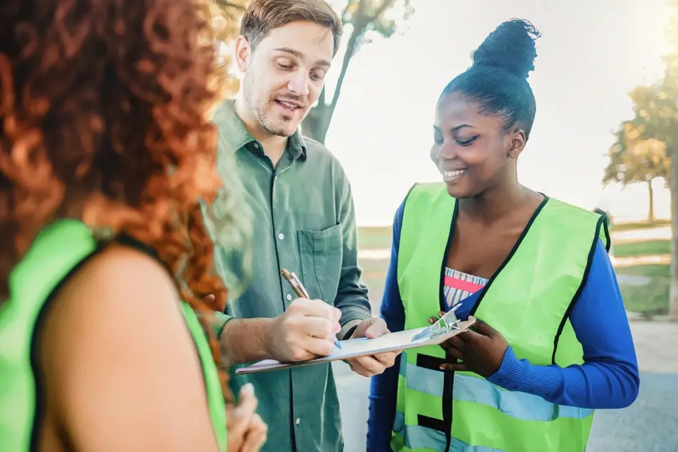 Volunteers collecting donations for an organization, asking a man to sign their clipboard