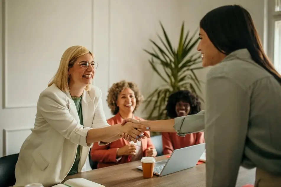 Mujeres se dan la mano sobre una mesa