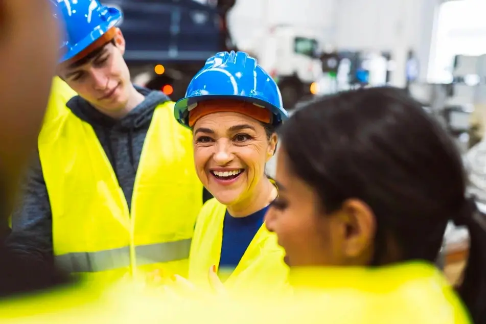 Mulher sorridente em meio a jovens uniformizados com equipamento de proteção