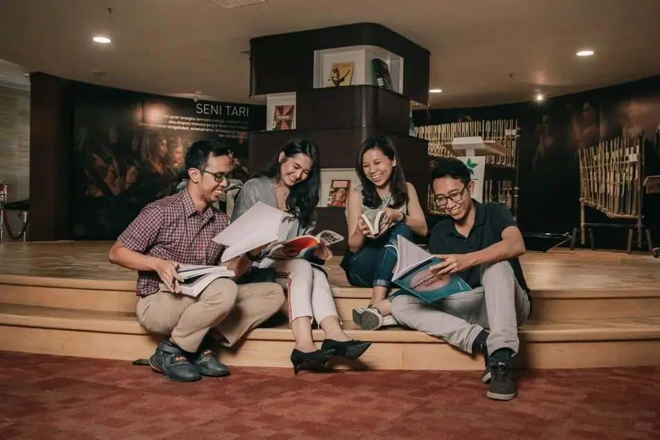two men and women smiling and reading books