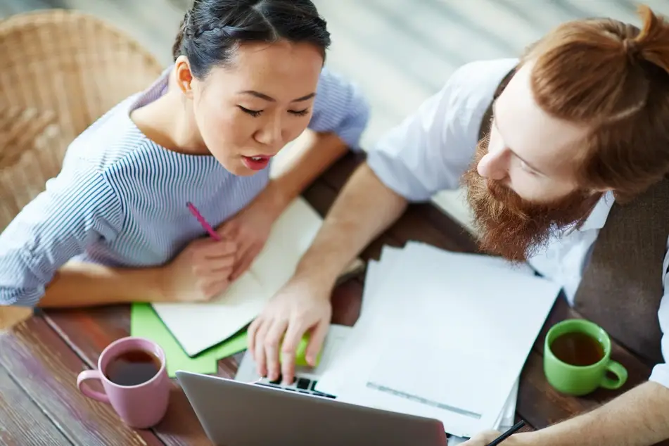 Two volunteers discuss project together on their laptop