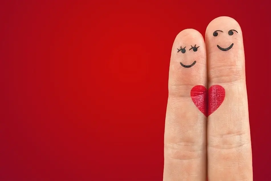 dos dedos juntos con un corazón pintado