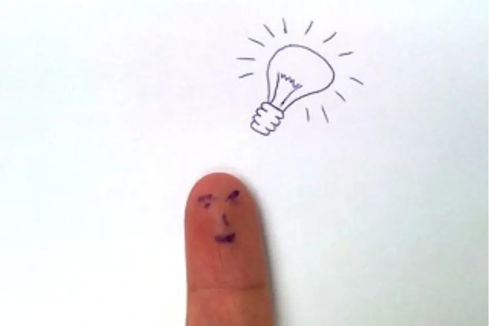 Una cara feliz pintada en un dedo sobre la cual está dibujada una bombilla (ícono de idea)