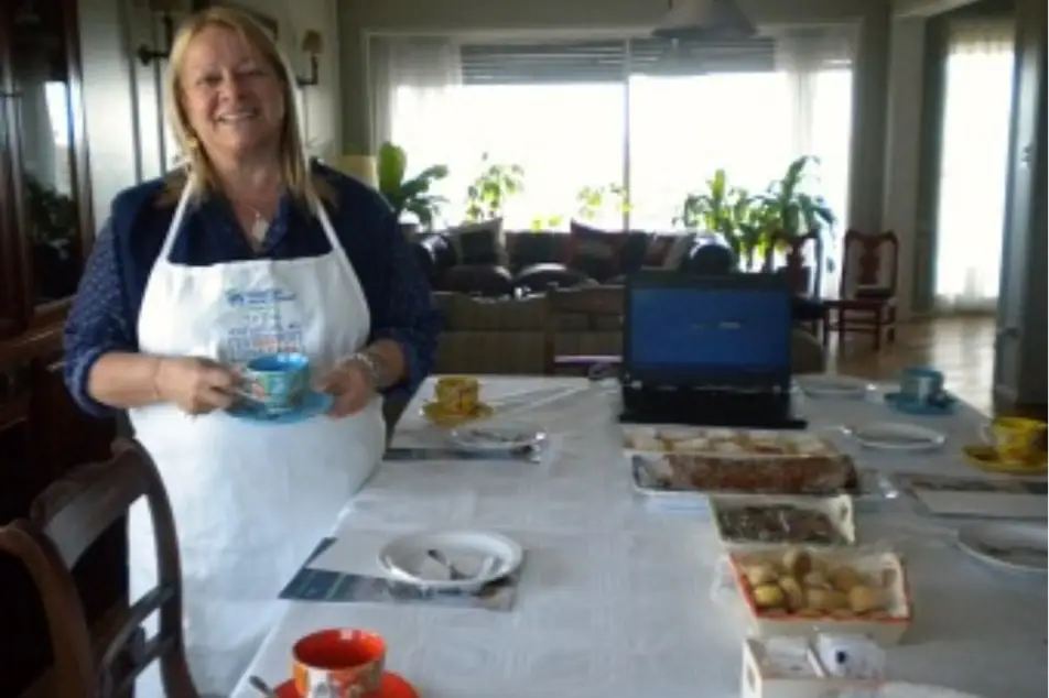Una mujer con delantal de cocina junto a la mesa servida en su casa