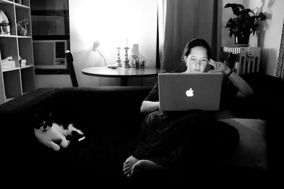 Una chica mirando a su computador portátil desde su casa