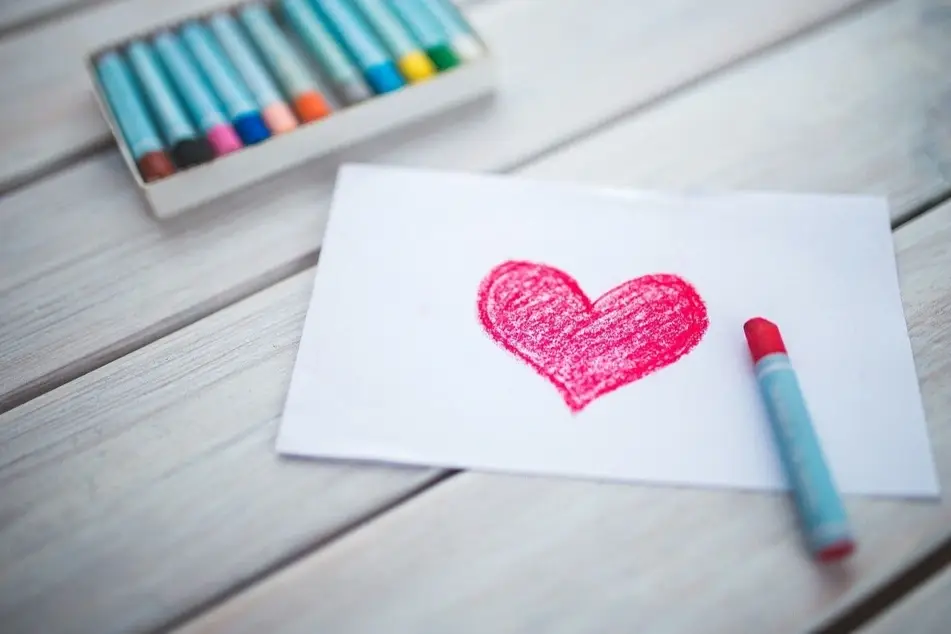 Un corazón pintado con colores que aparecen al fondo de la imagen