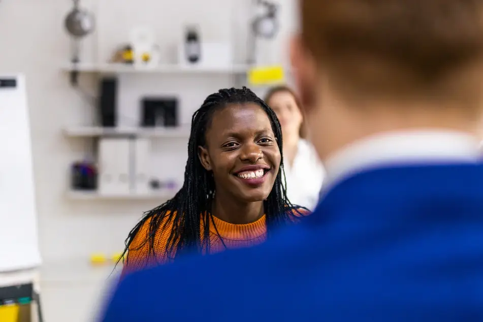 Two people smile while networking at work