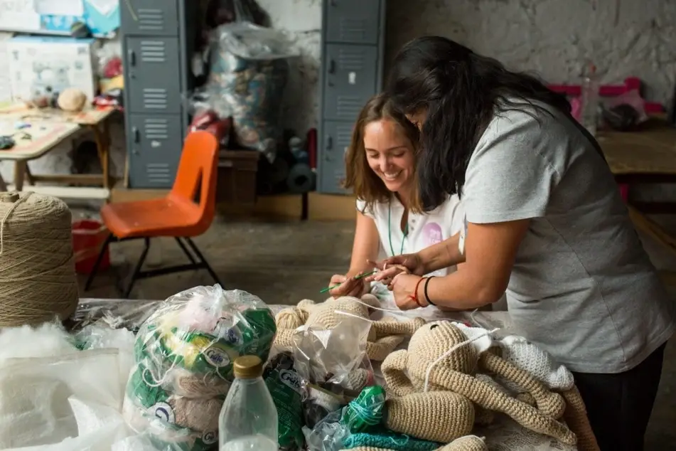 Dos mujeres riendo mientras tejen juntas
