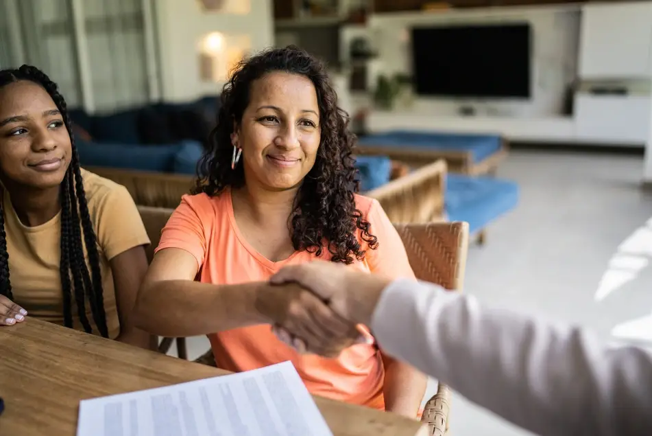 two woman smiling one shaking hands