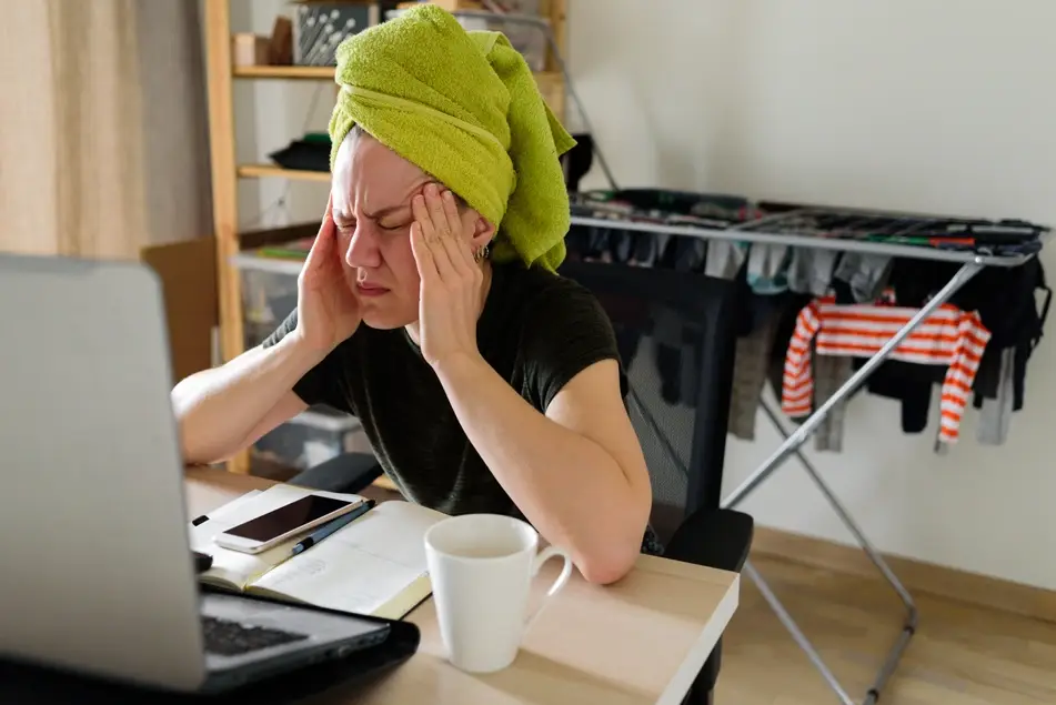 Stressed woman towel-drying hair at home navigates a layoff at home.