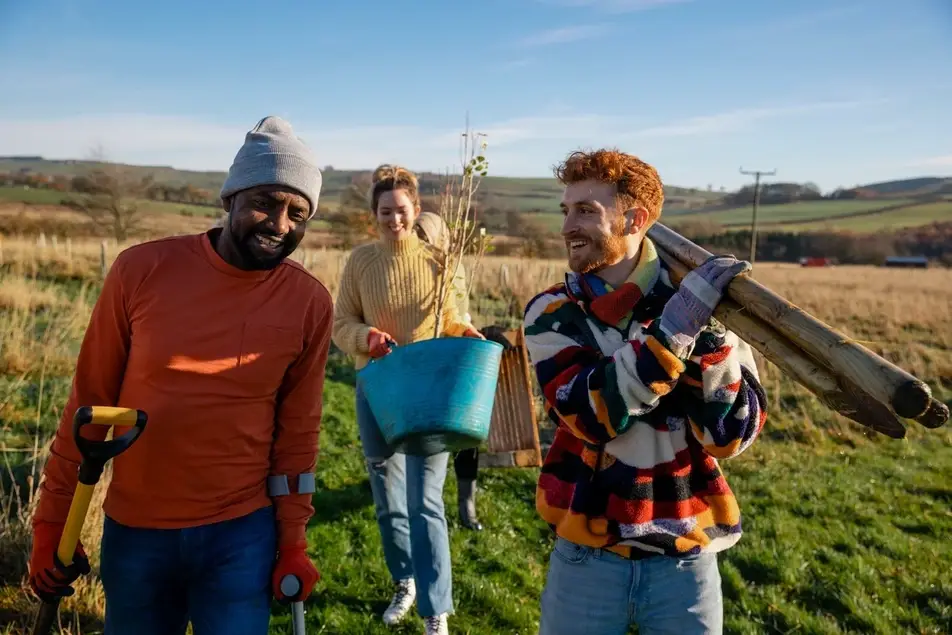 People laughing while planting a tree