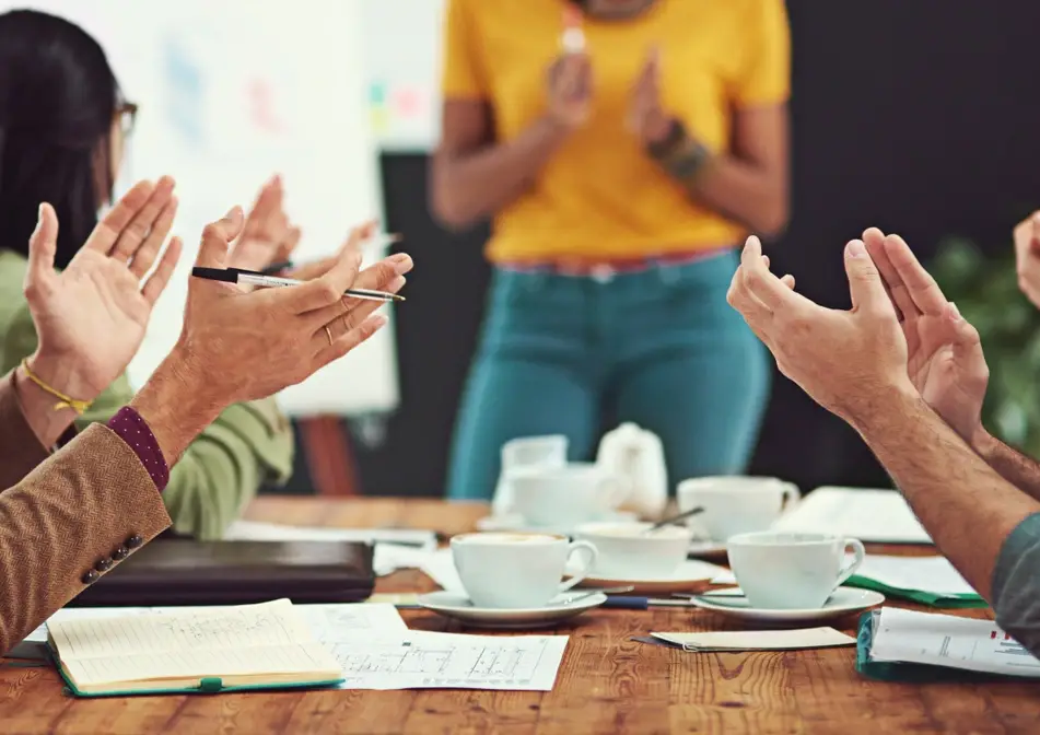 Group of volunteers applaud a speaker at a table