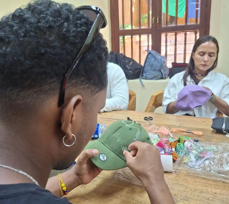 Participante bordando una gorra durante la iniciativa “Manos que transforman” en Colombia.