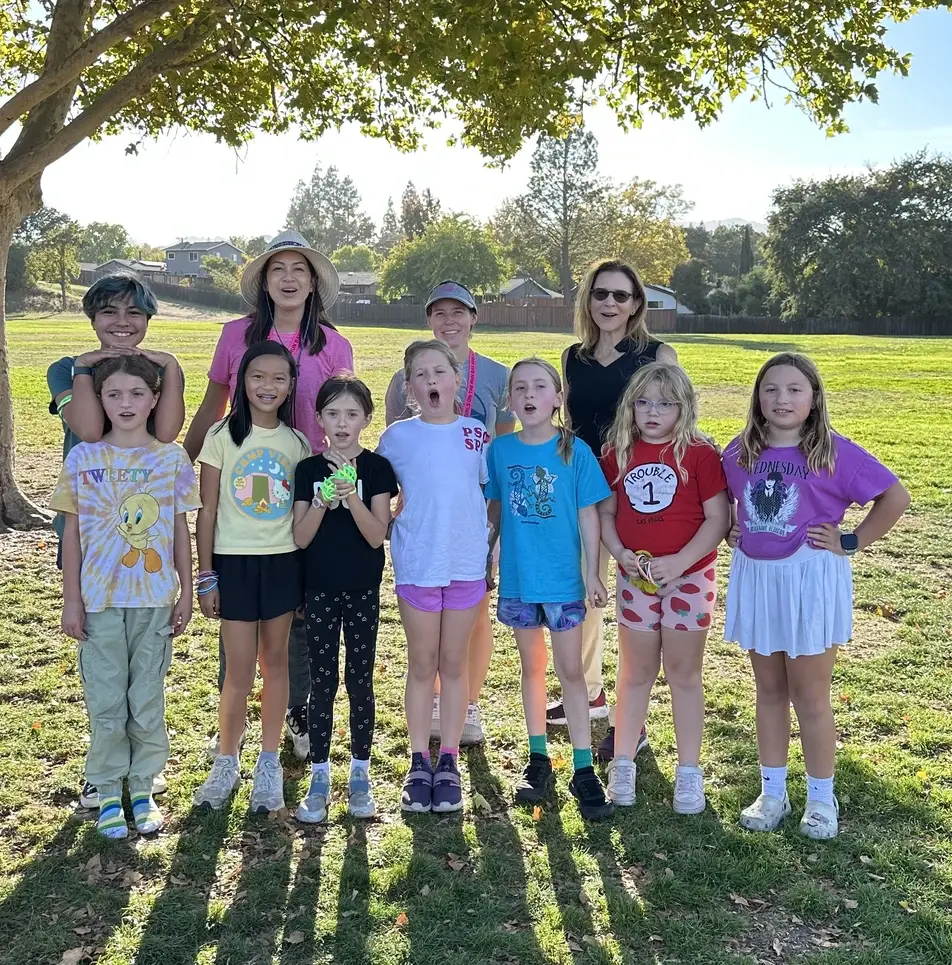Volunteer Coach Gail smiles with a group of young girls part of Girls on the Run.